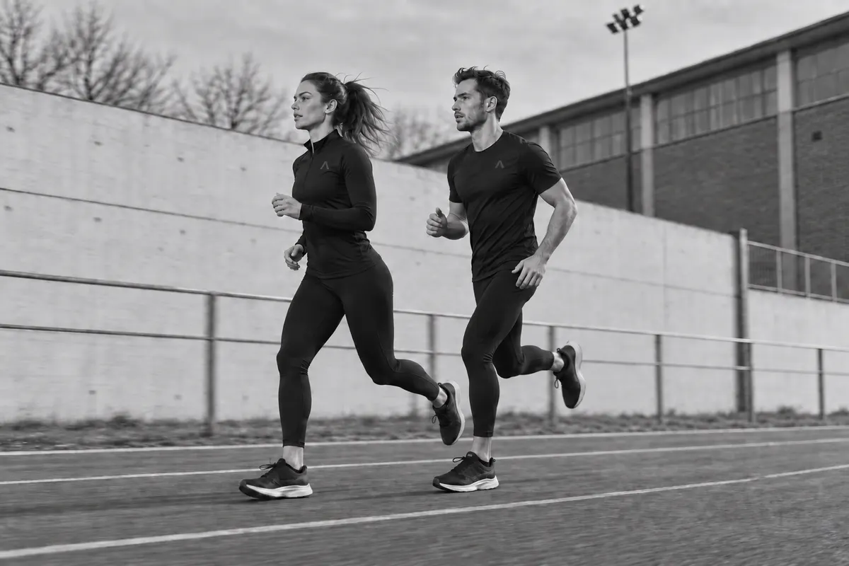 Dwoje biegaczy na bieżni przy ośrodku sportowym, zdjęcie czarno-białe